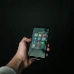 hand scrolling holding phone with social media icons, is there porn on instagram all you need to know
